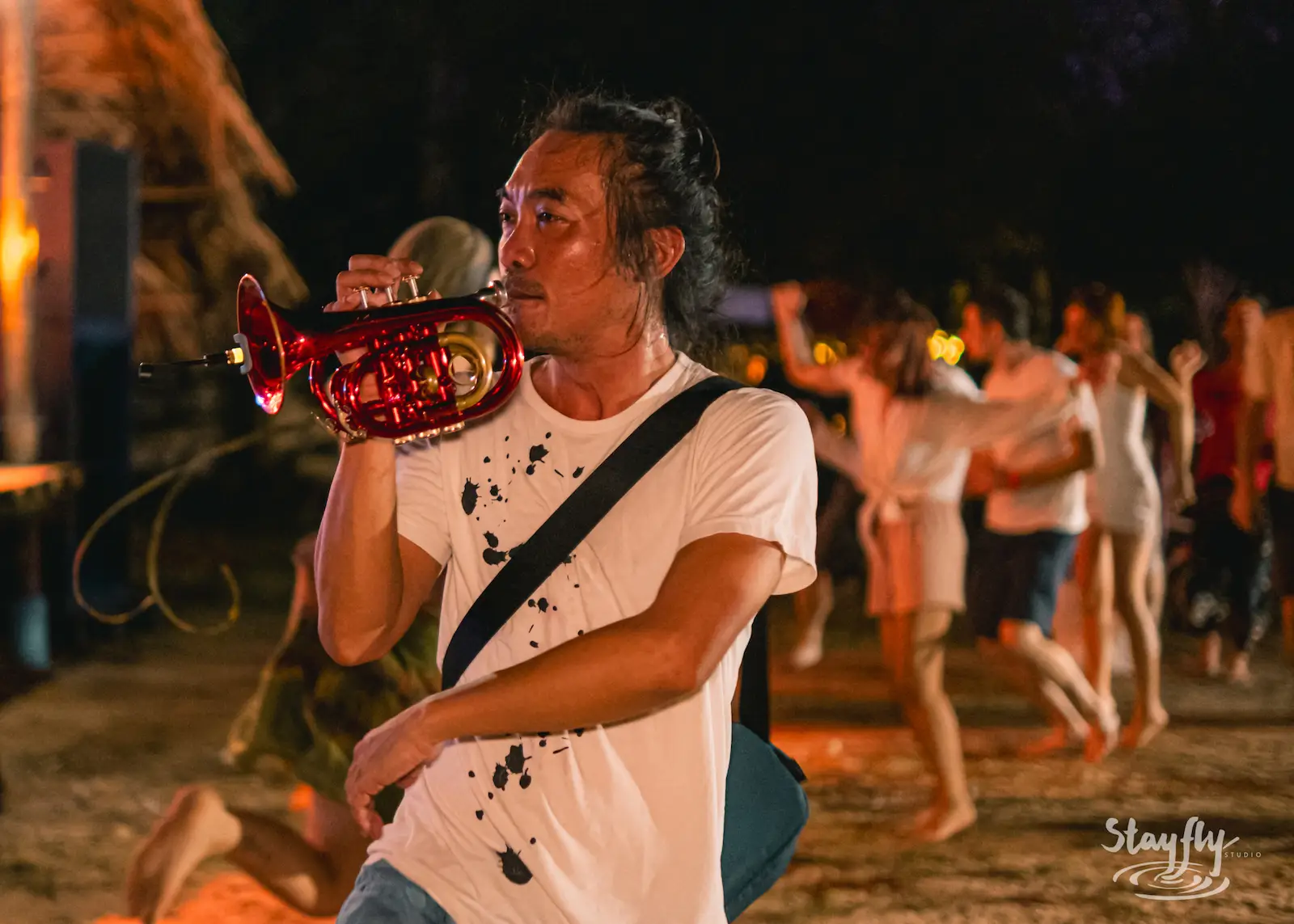 Man playing trumpet amid a dancing crowd.
