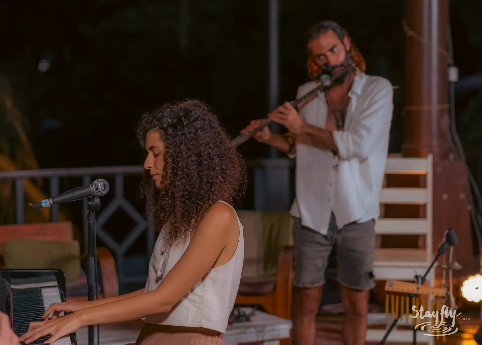 Pianist and flutist perform evening stage duet.