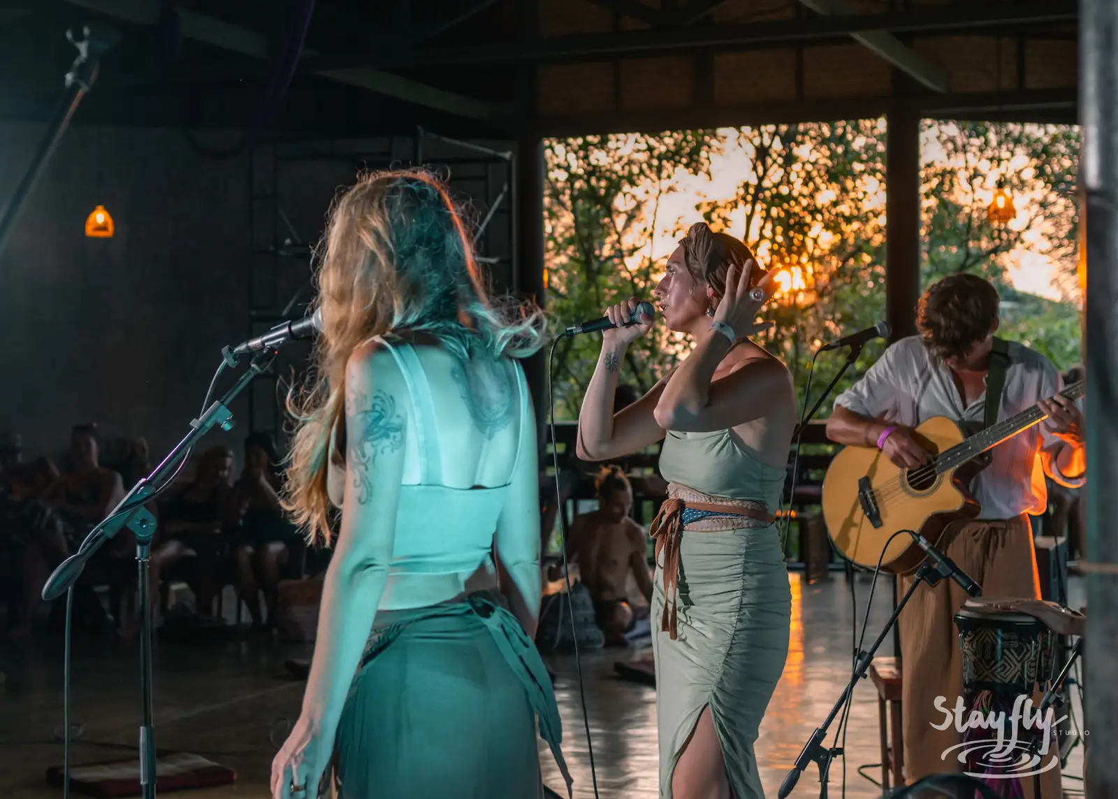 Two women sing together at sunset stage.