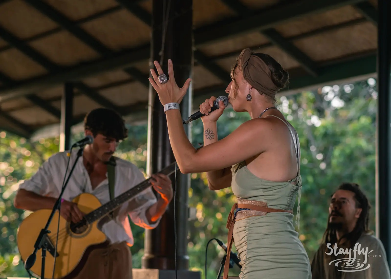 Singer performs with guitarist in daytime venue.