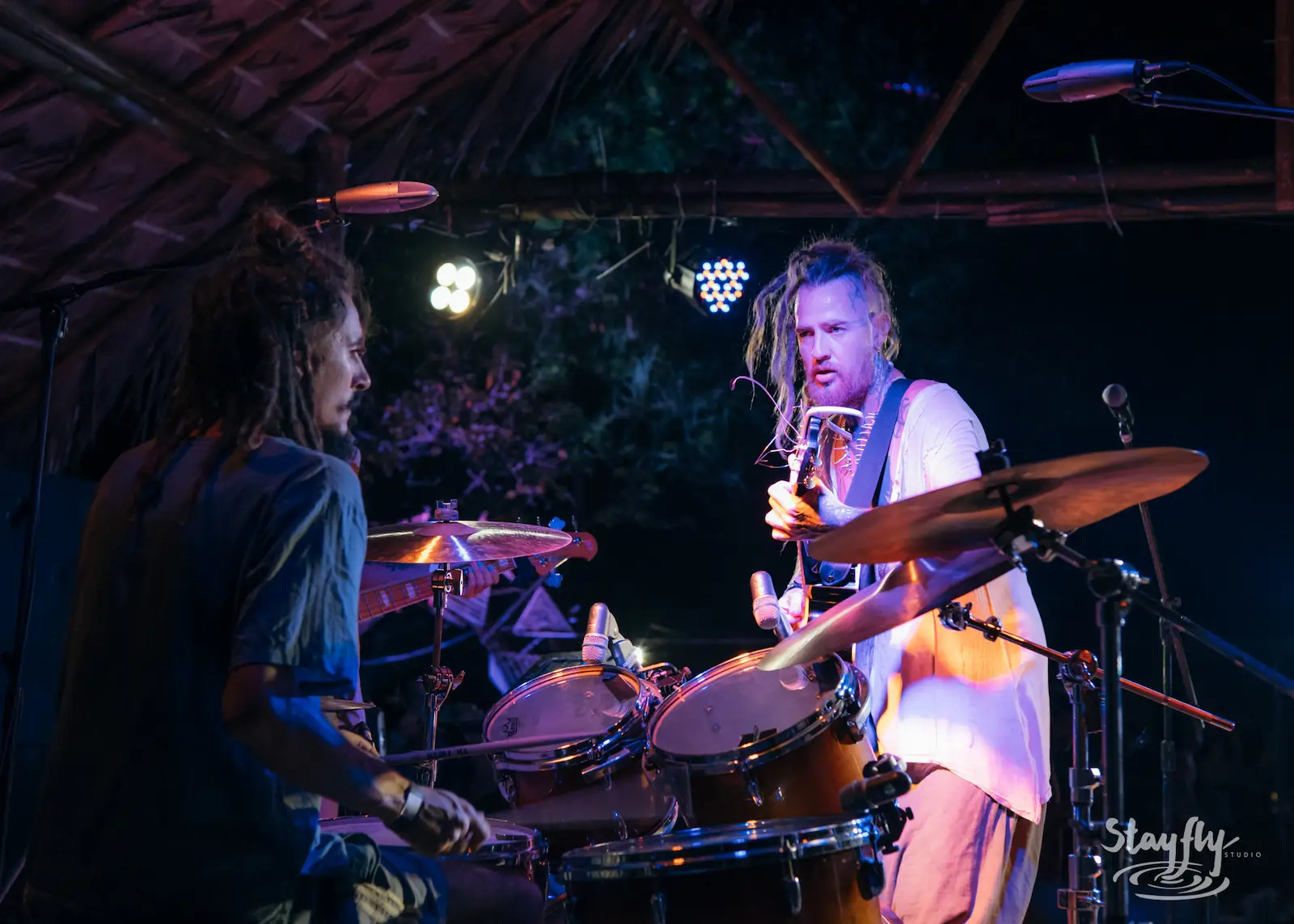 Two musicians on stage, drums and guitar.