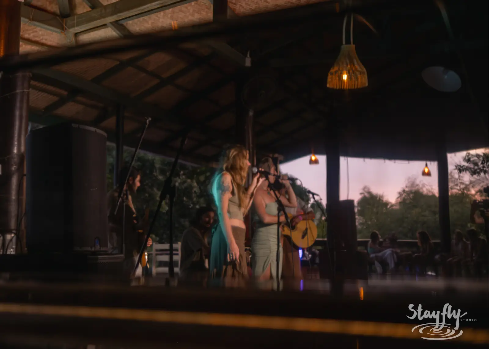 Singers performing on open-air stage at dusk.