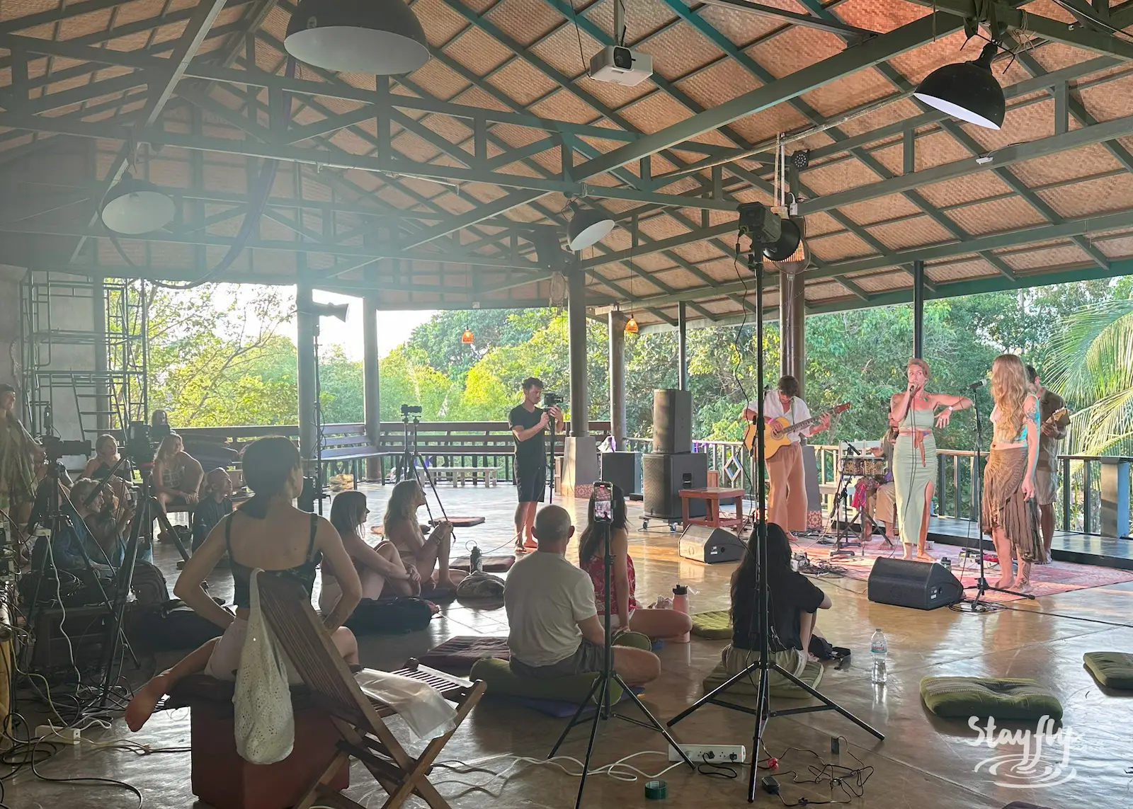 Band performing to seated crowd in open pavilion.