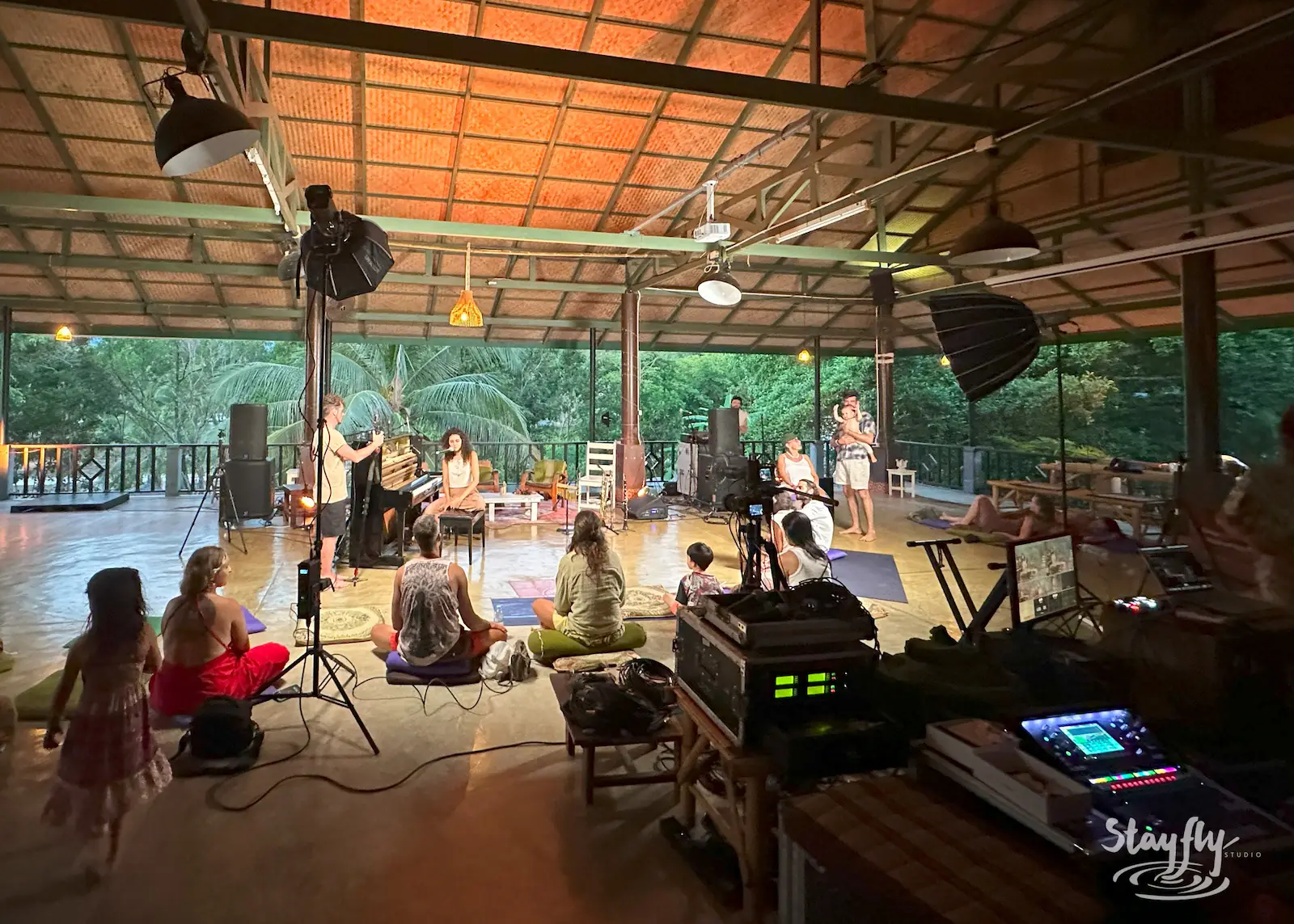 Musicians and crew perform under open-air roof.
