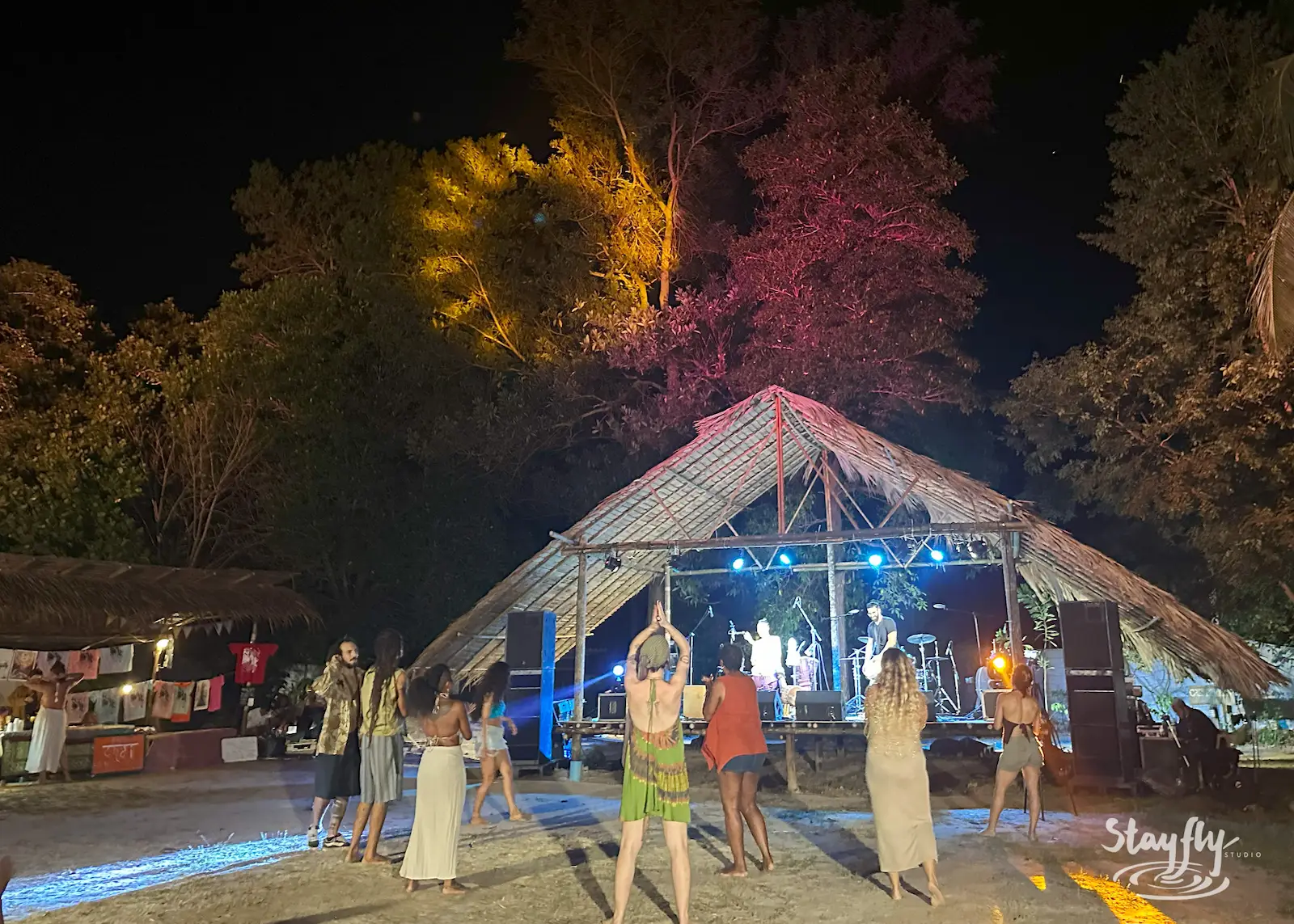 Dancers perform on bamboo pyramid stage at night.