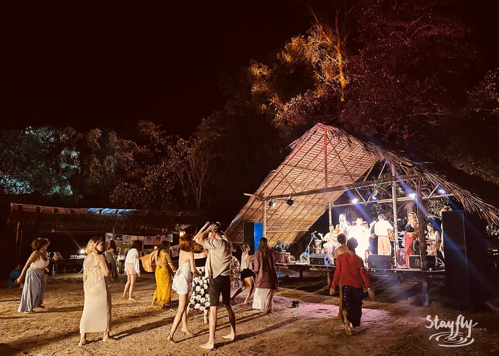 Crowd dances near lit bamboo pyramid stage.