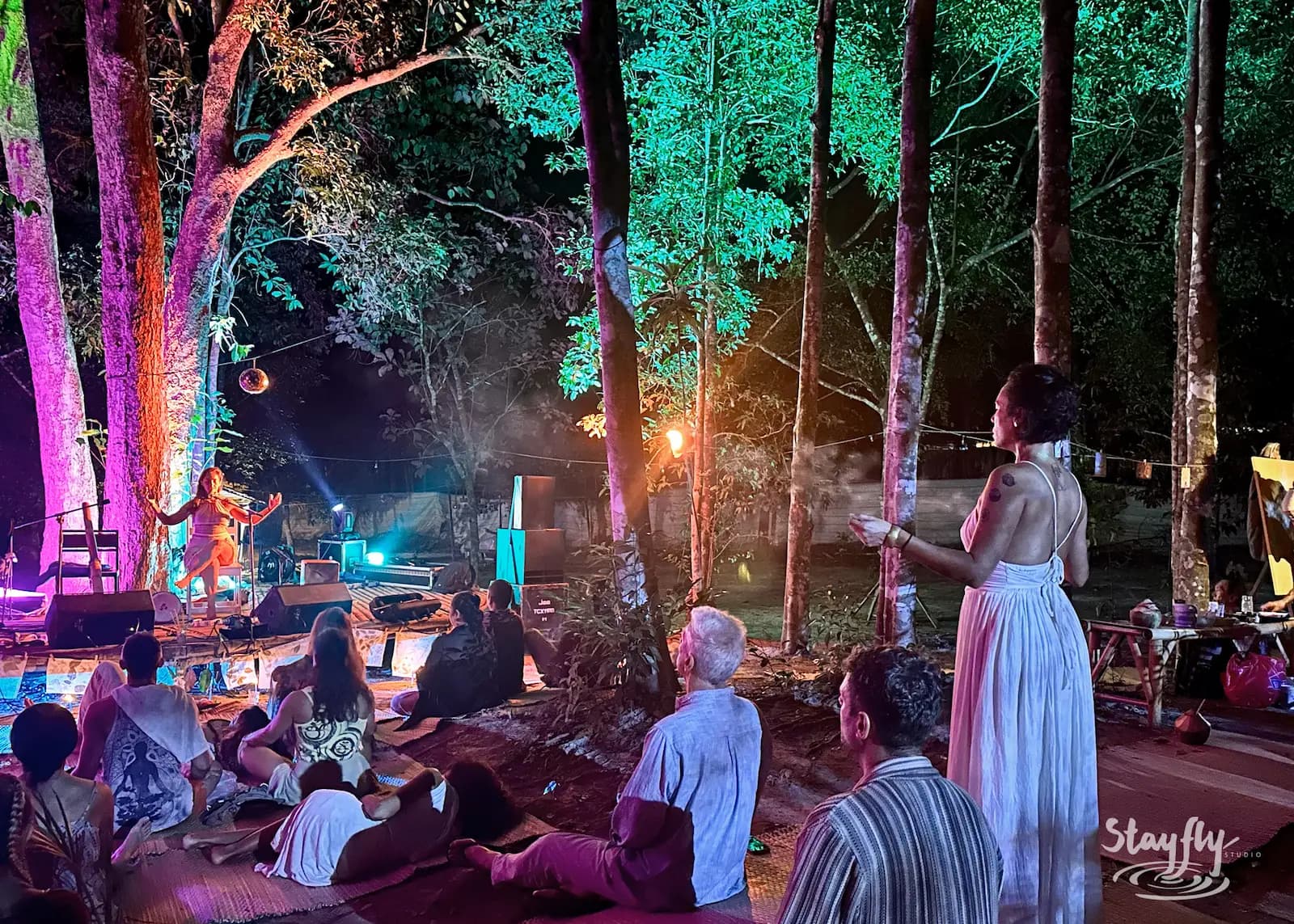 Woman in white watches distant night stage.