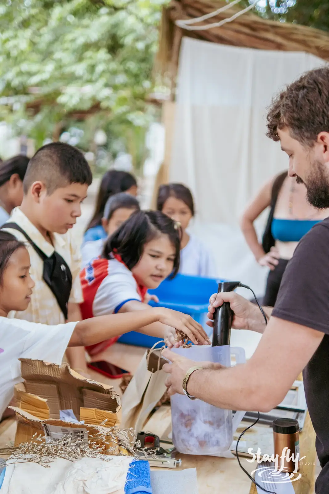 Children gather at a market craft stall.