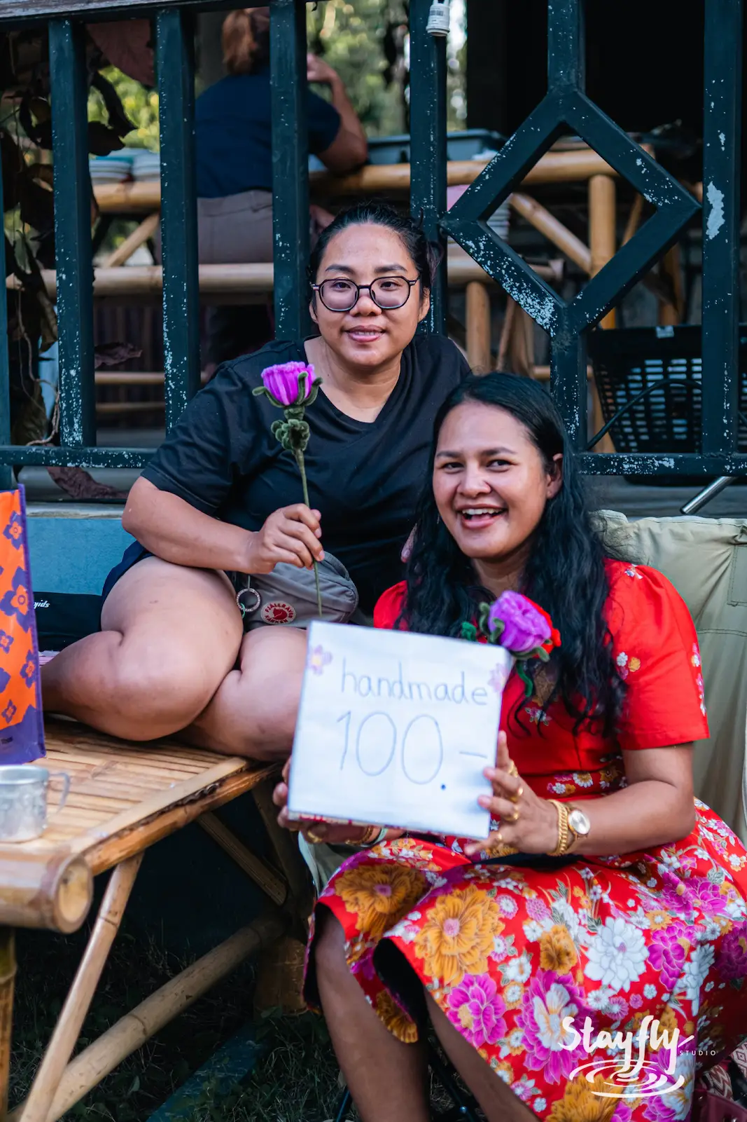 Two women pose with a handmade craft sign.