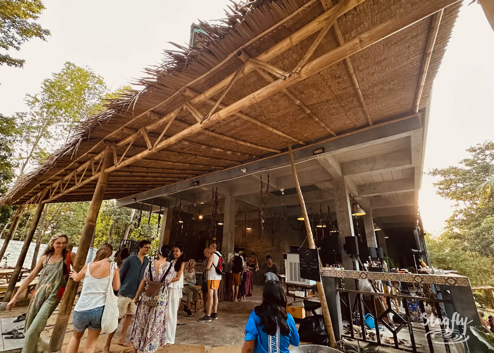 Visitors entering thatched market and food building.