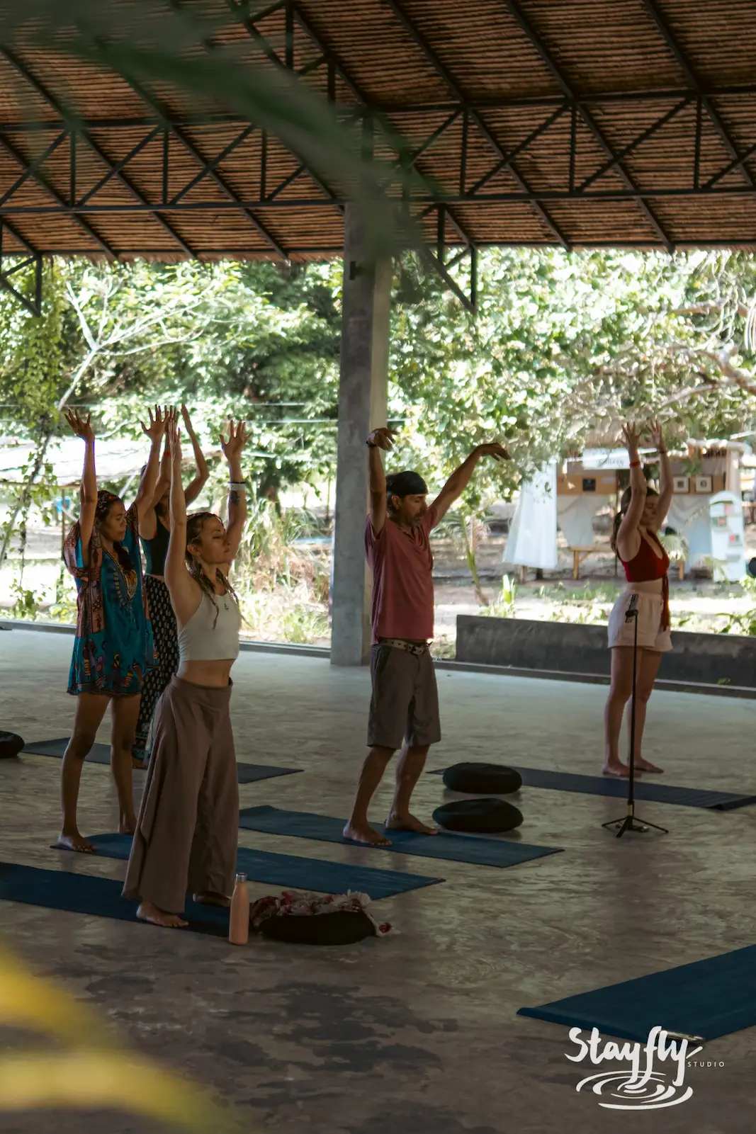 Group yoga class reaching arms upward.