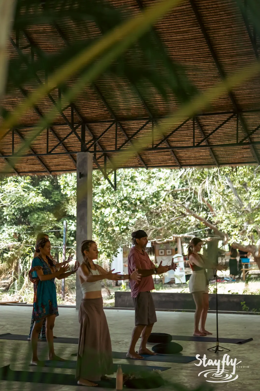 Four practitioners hold a yoga pose outdoors.