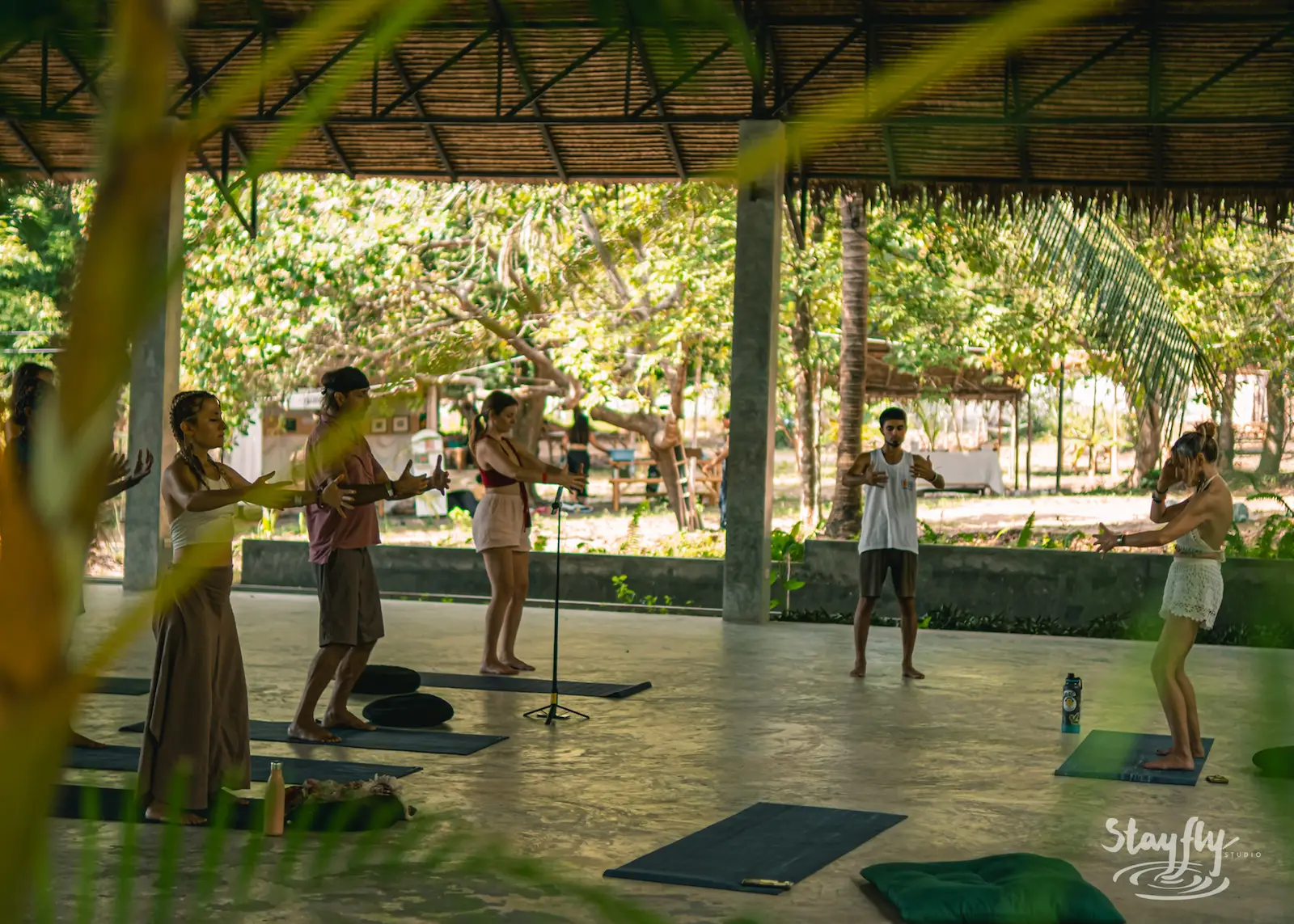 Group practices yoga poses in pavilion.