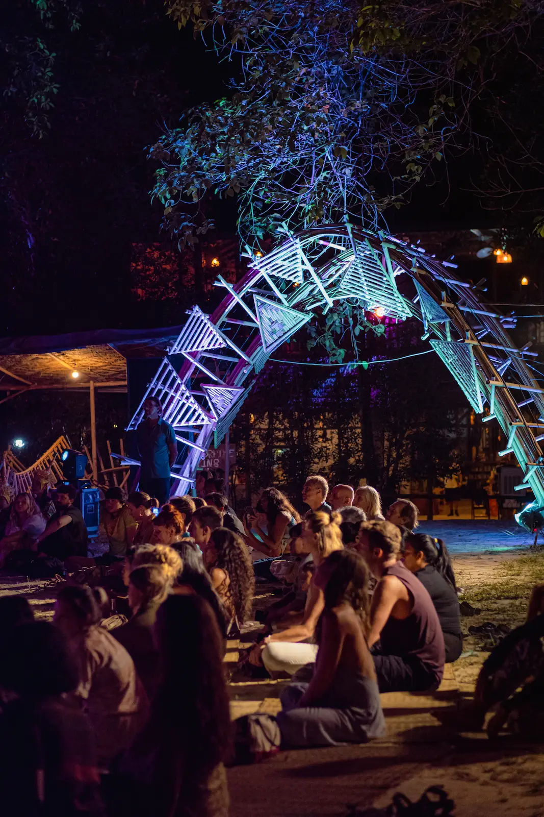 Crowd gathers beneath illuminated dome archway at night.