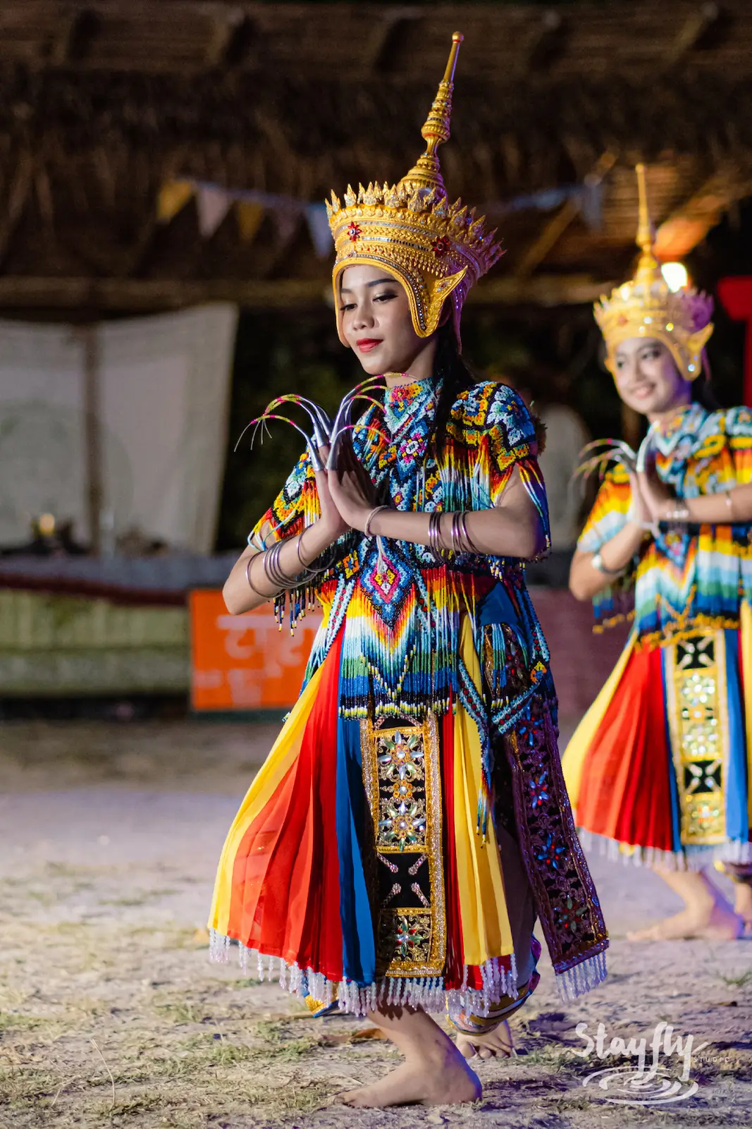 Two costumed Thai dancers performing at night.