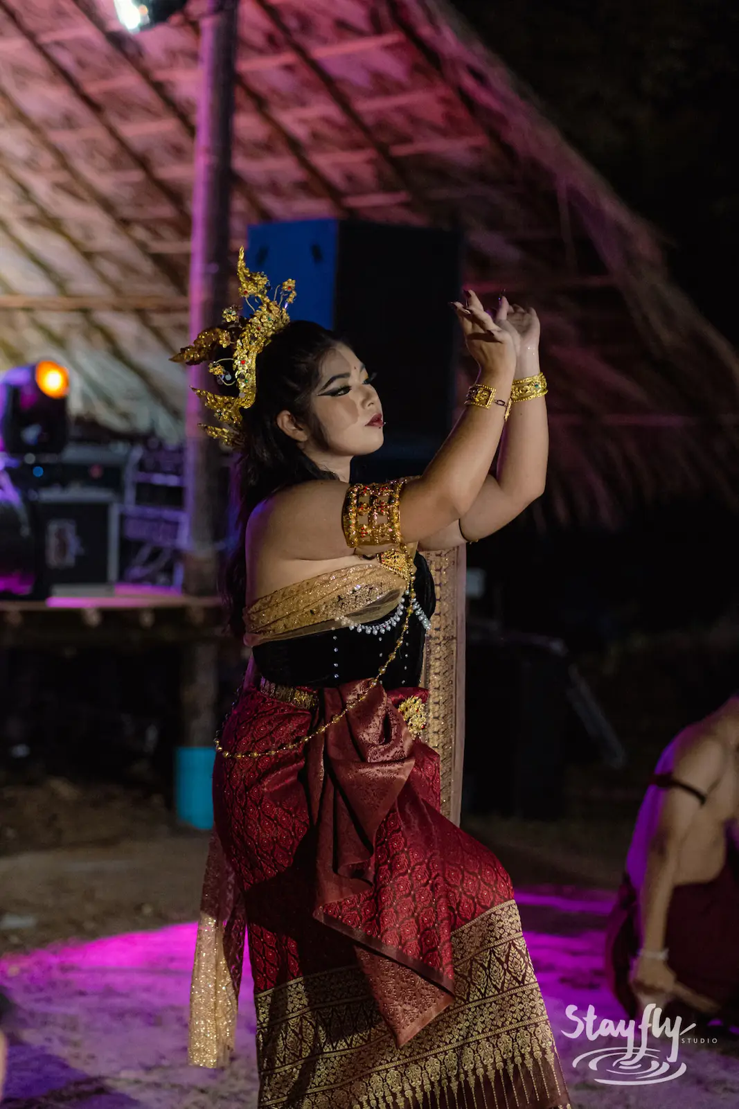 Dancer in red and gold costume near sound gear.
