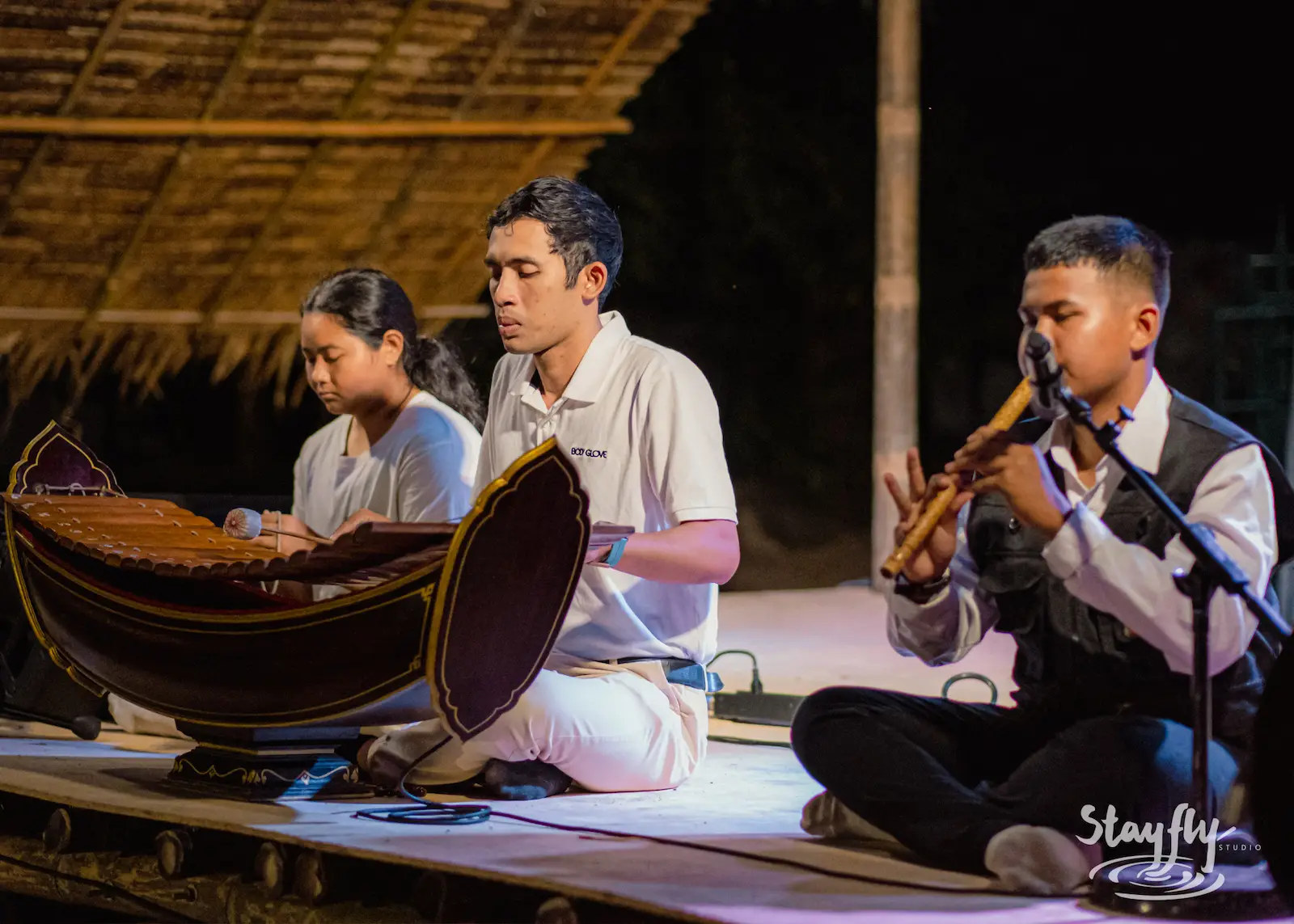 Trio performs traditional Thai instruments seated.