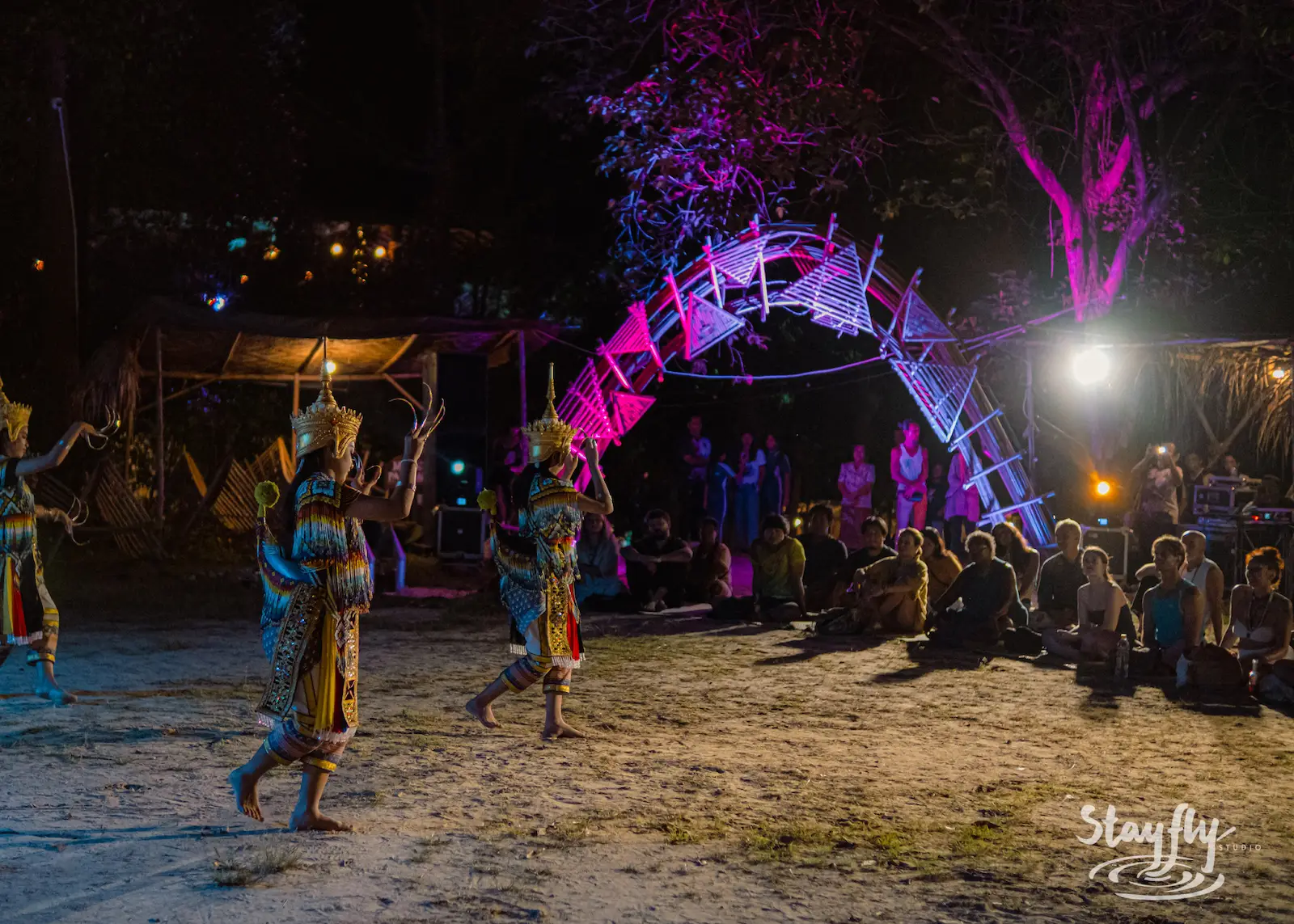 Dancers walk toward glowing purple arch.