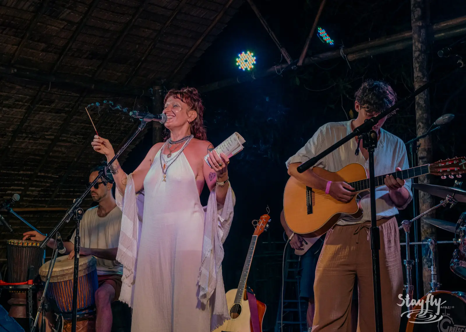 Robed woman blessing stage alongside musicians.