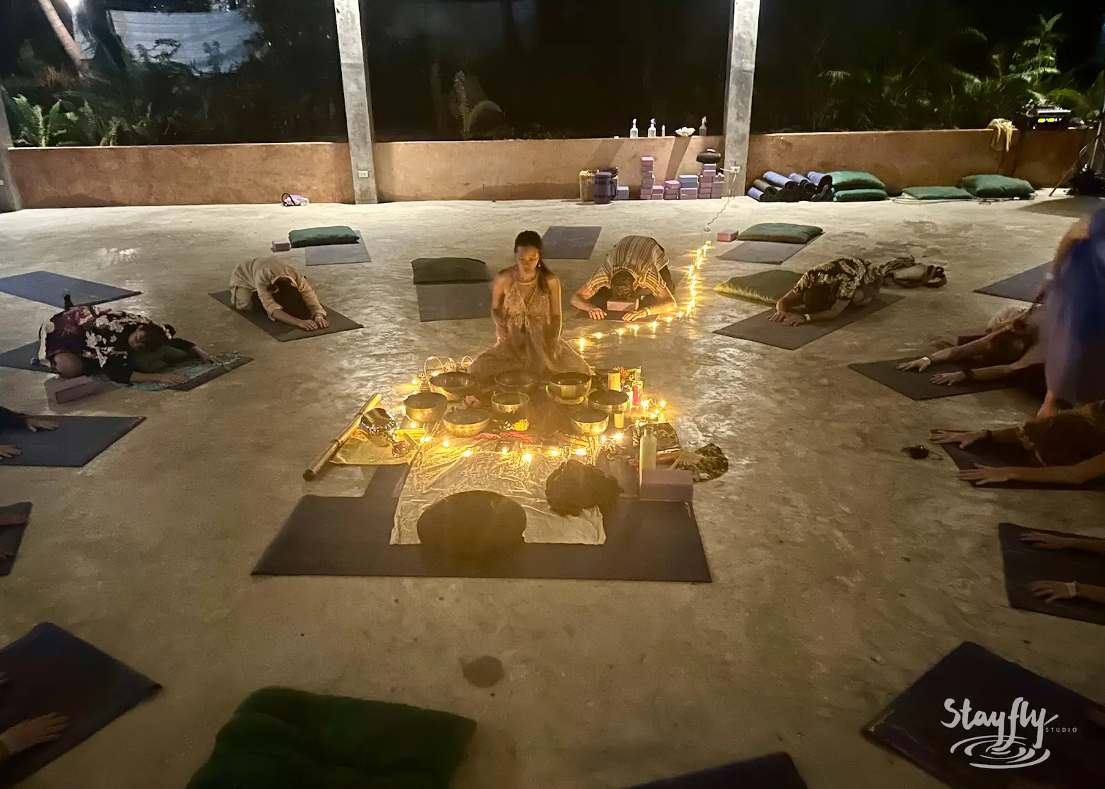 Solo ritual performer inside candlelit mandala of mats.