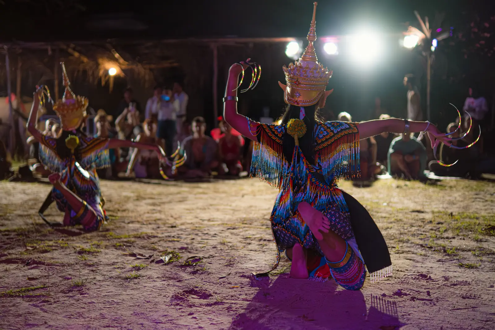 Two costumed dancers strike dramatic crouching pose.
