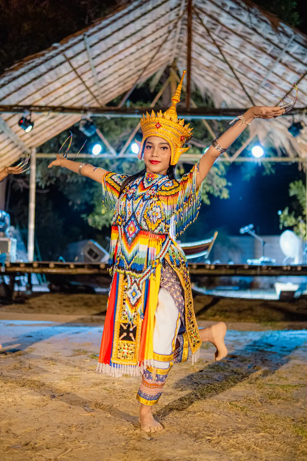 Girl dancer balances in gold crown, arms raised.