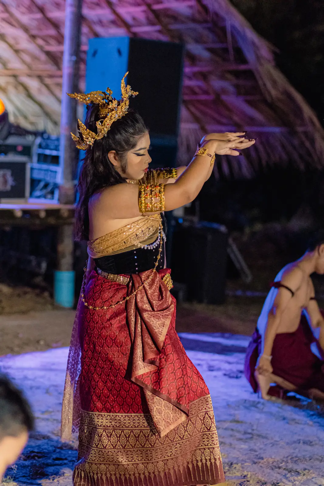 Dancer in red skirt and gold headdress mid-move.