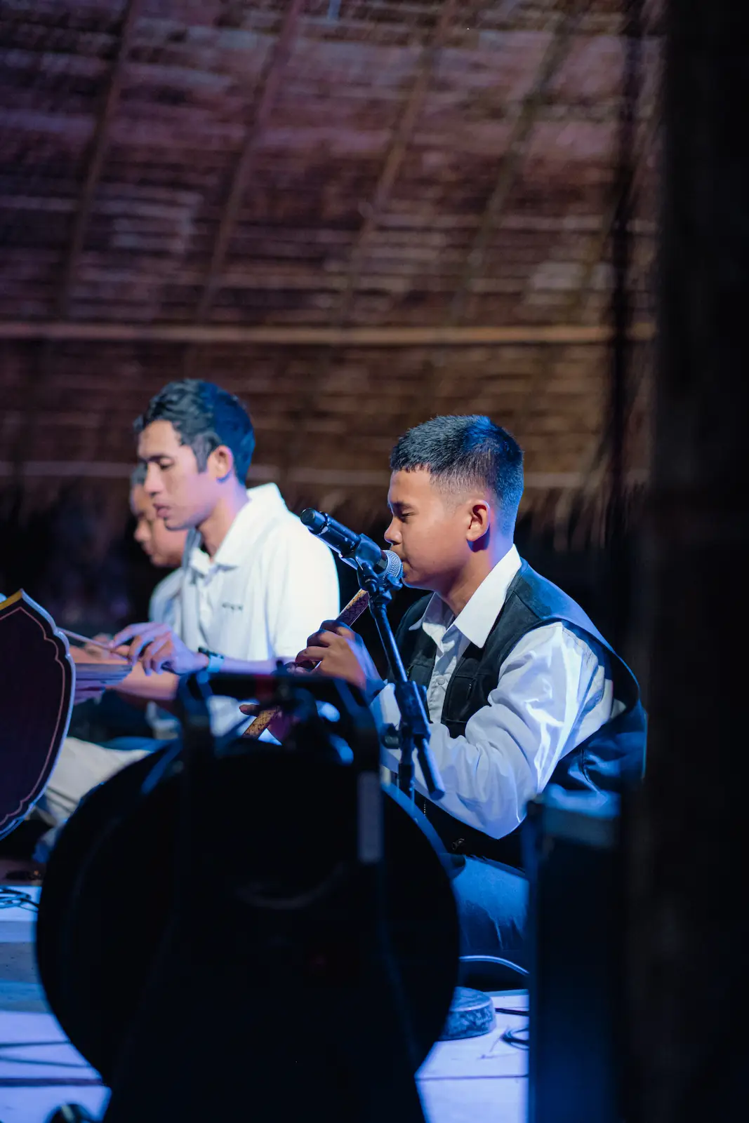 Teen musicians play flute and drum on stage.