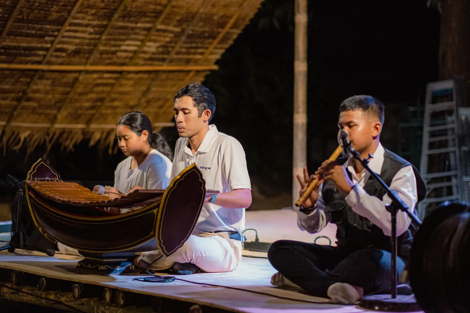Three musicians play traditional Thai instruments on stage.
