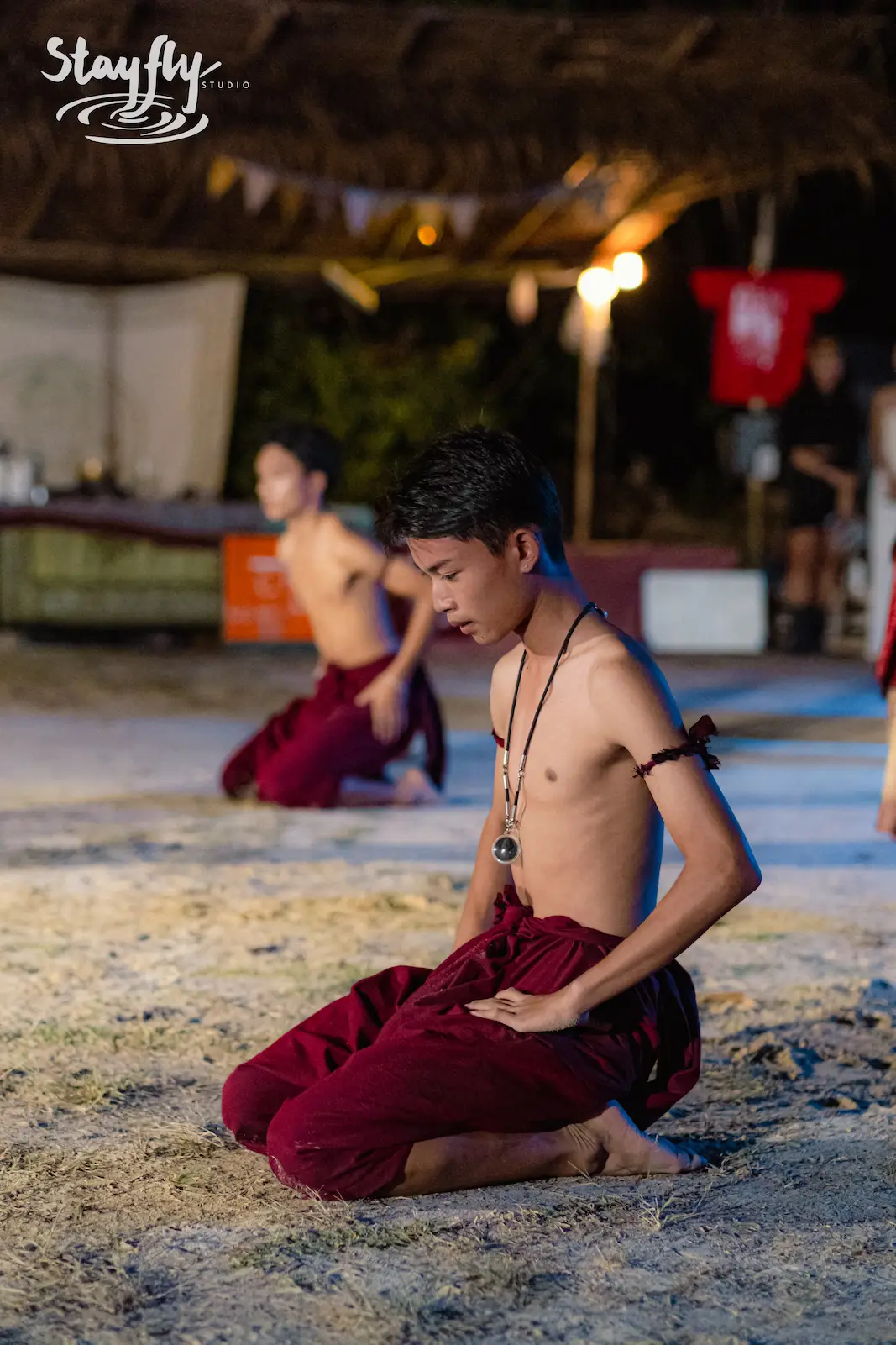Young performer kneeling in meditative costume pose.