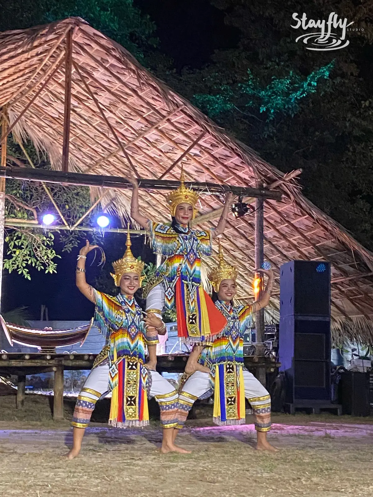 Three costumed dancers posed on night stage.