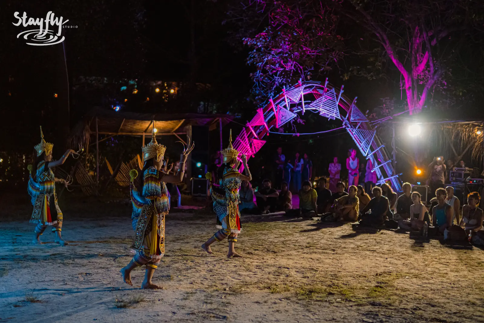 Costumed dancers approach glowing arch before audience.