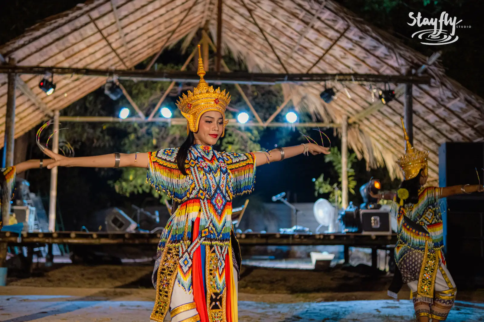 Solo dancer with golden crown, arms wide.
