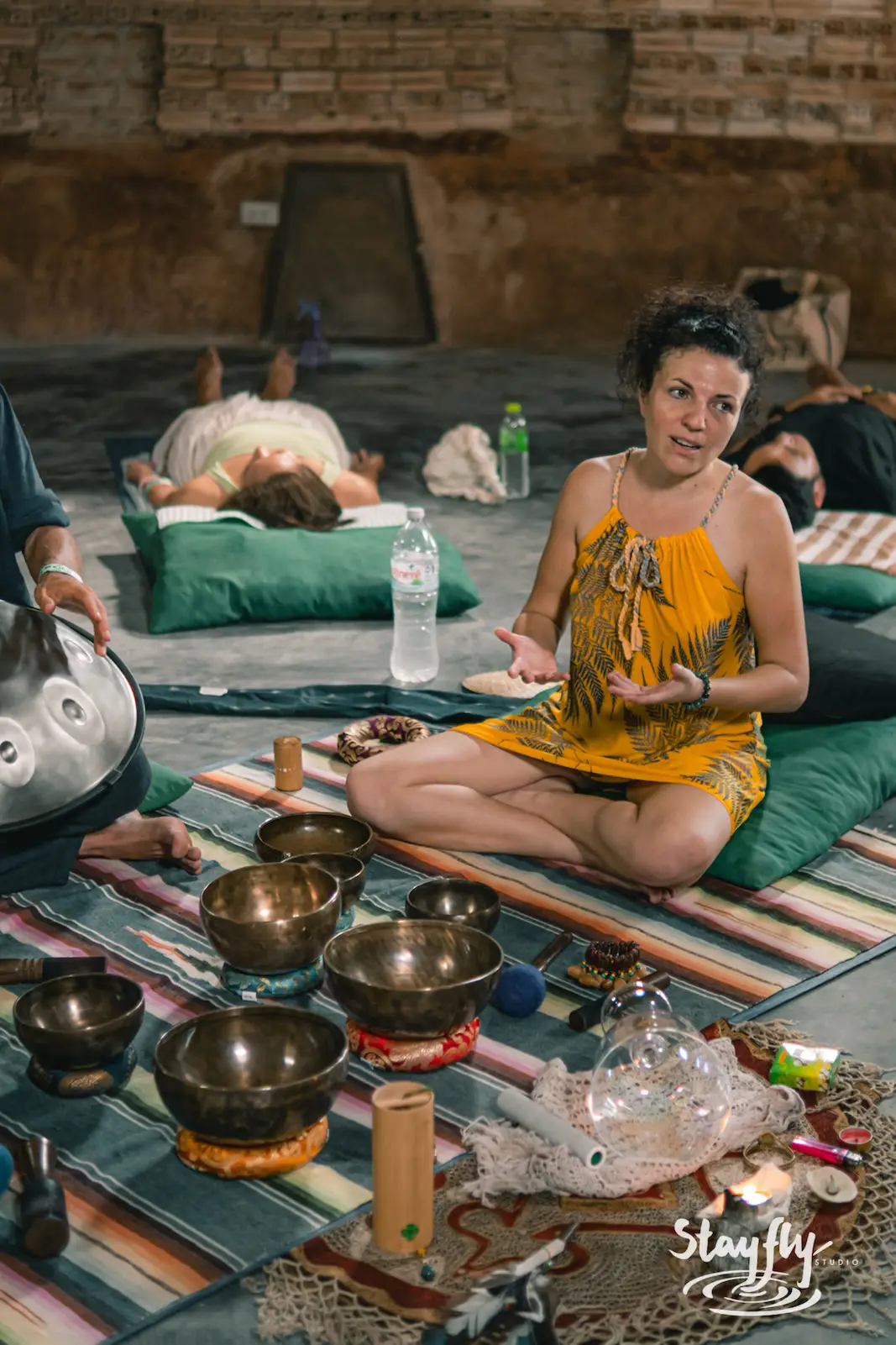 Woman leads sound bath session in yellow dress.