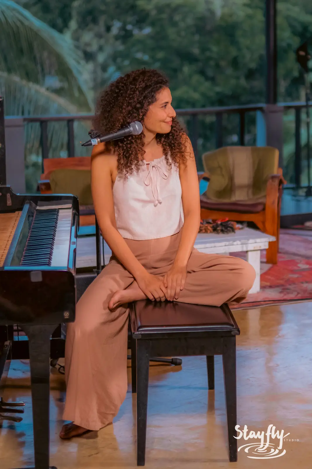 Woman seated on piano bench, thoughtful pose.