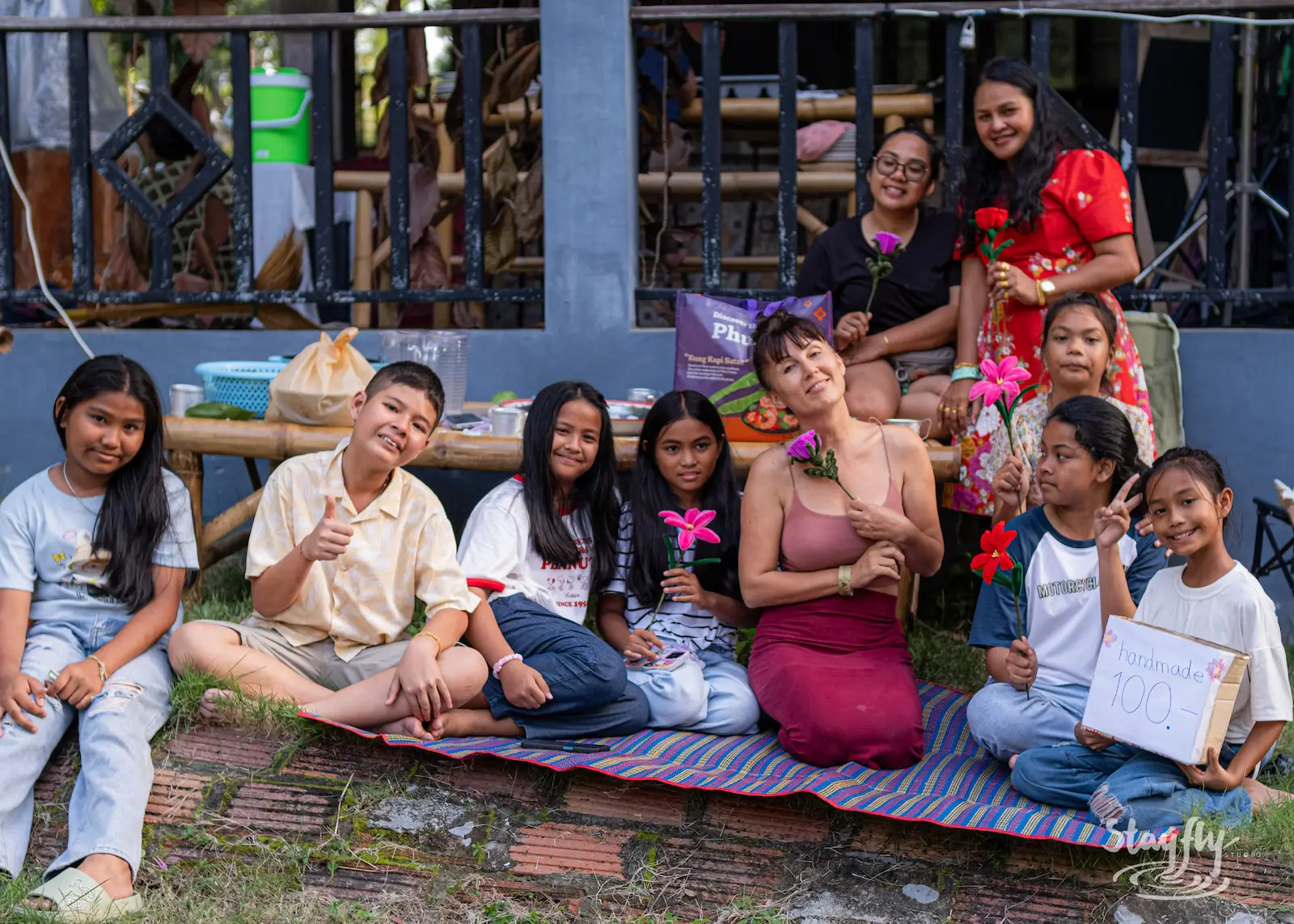 Group poses together with flowers outdoors.