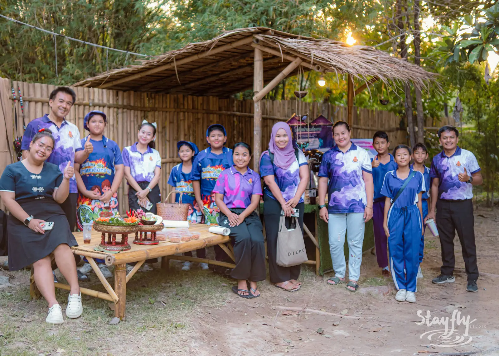 School group poses with staff under shelter.