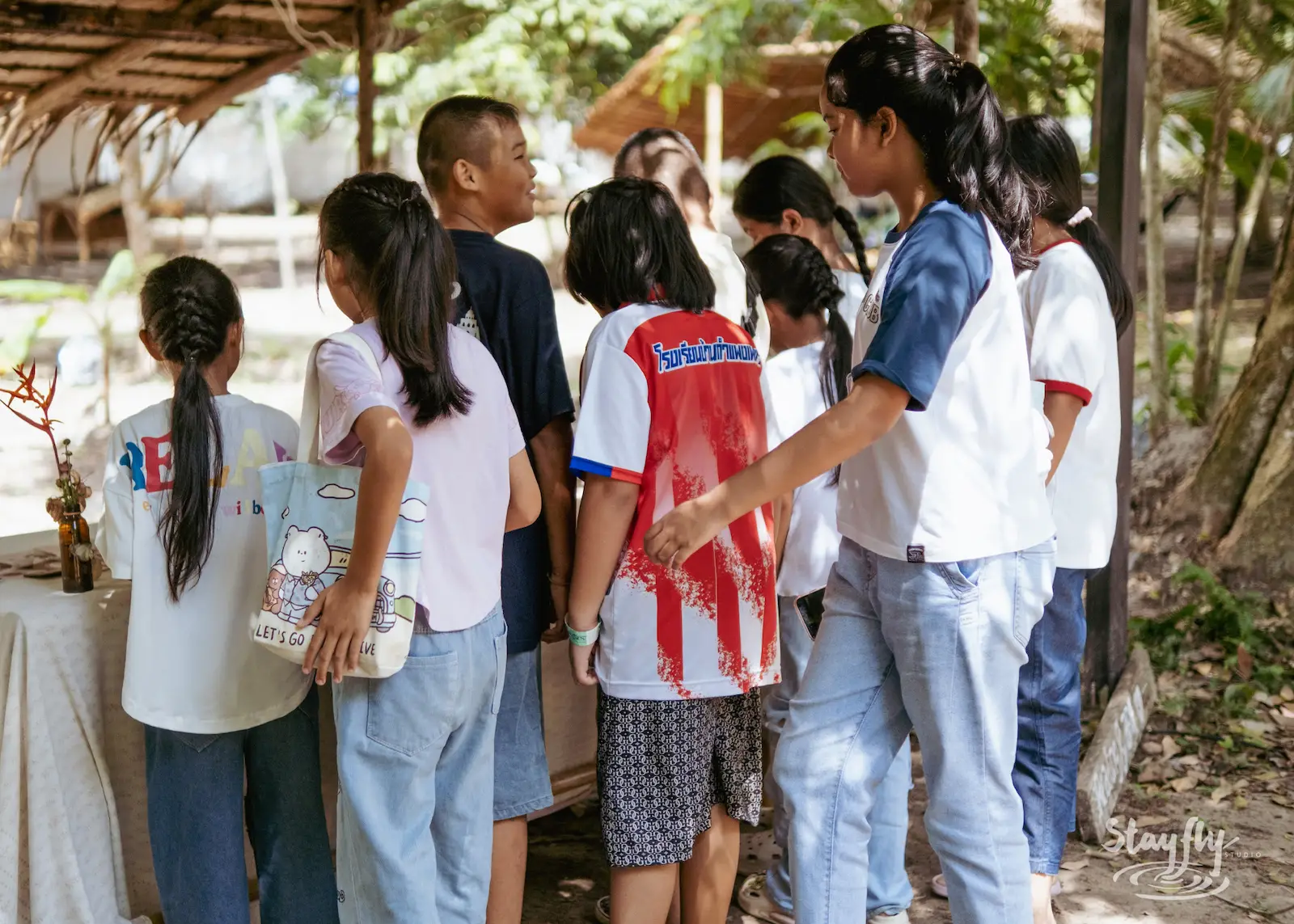 Children walk together under outdoor shelter.