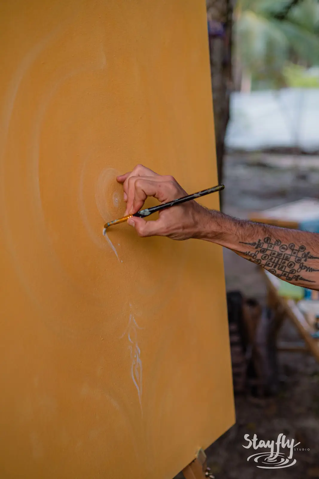 Close up of hand painting a yellow canvas.