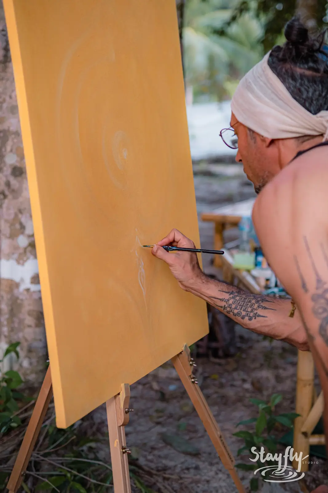Man painting an outdoor canvas, wide shot.
