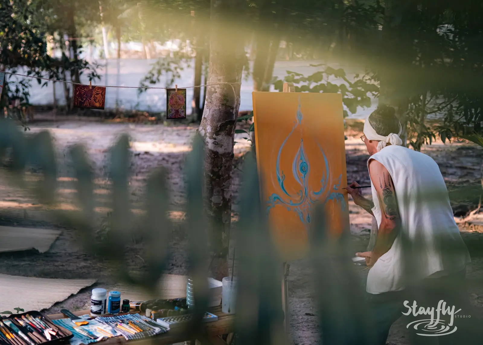 Artist paints outdoors among trees.