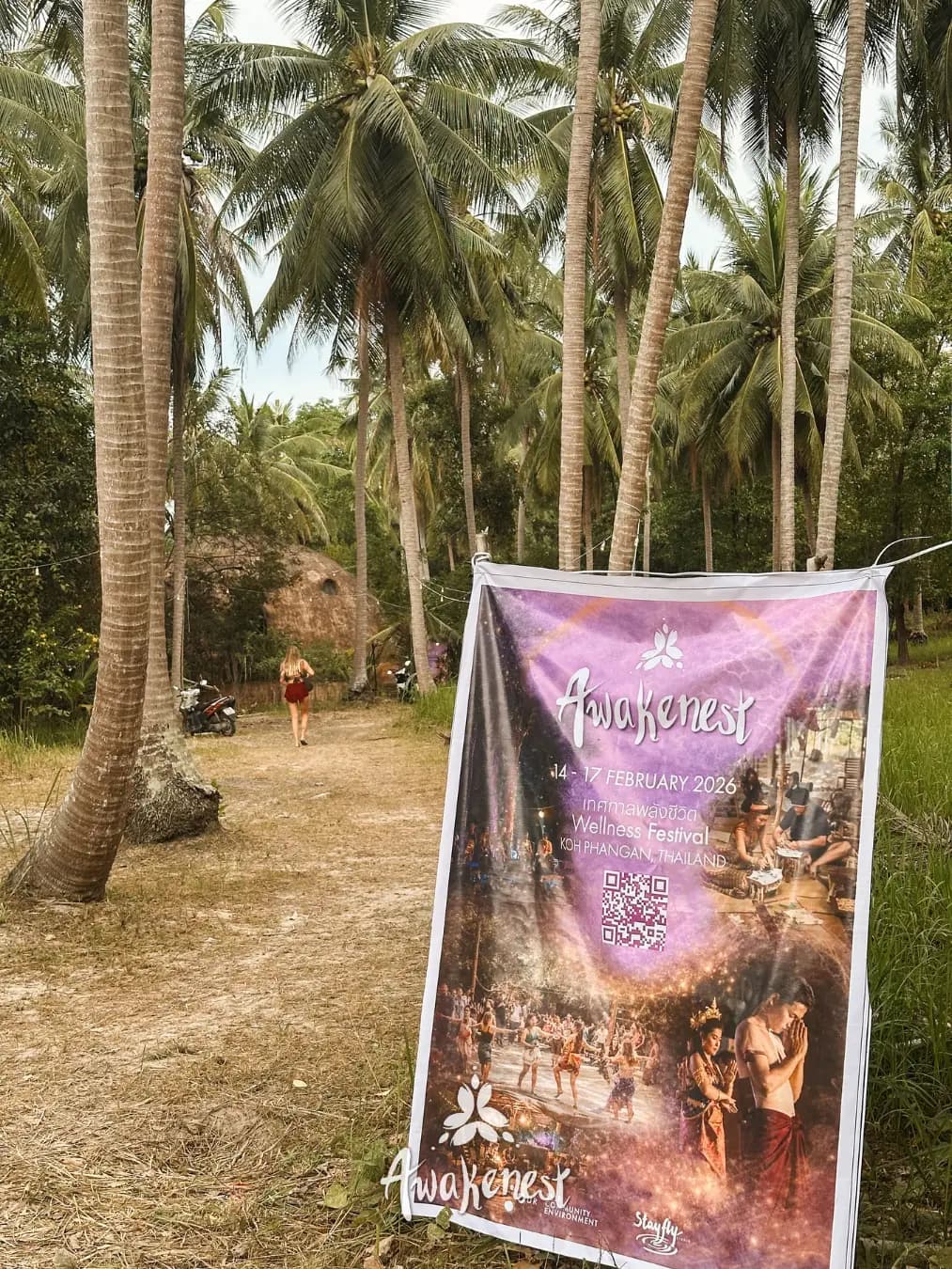 Awakenest festival poster hanging among palms.