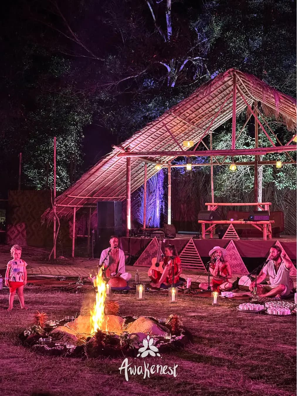 Child in foreground near group around night fire.