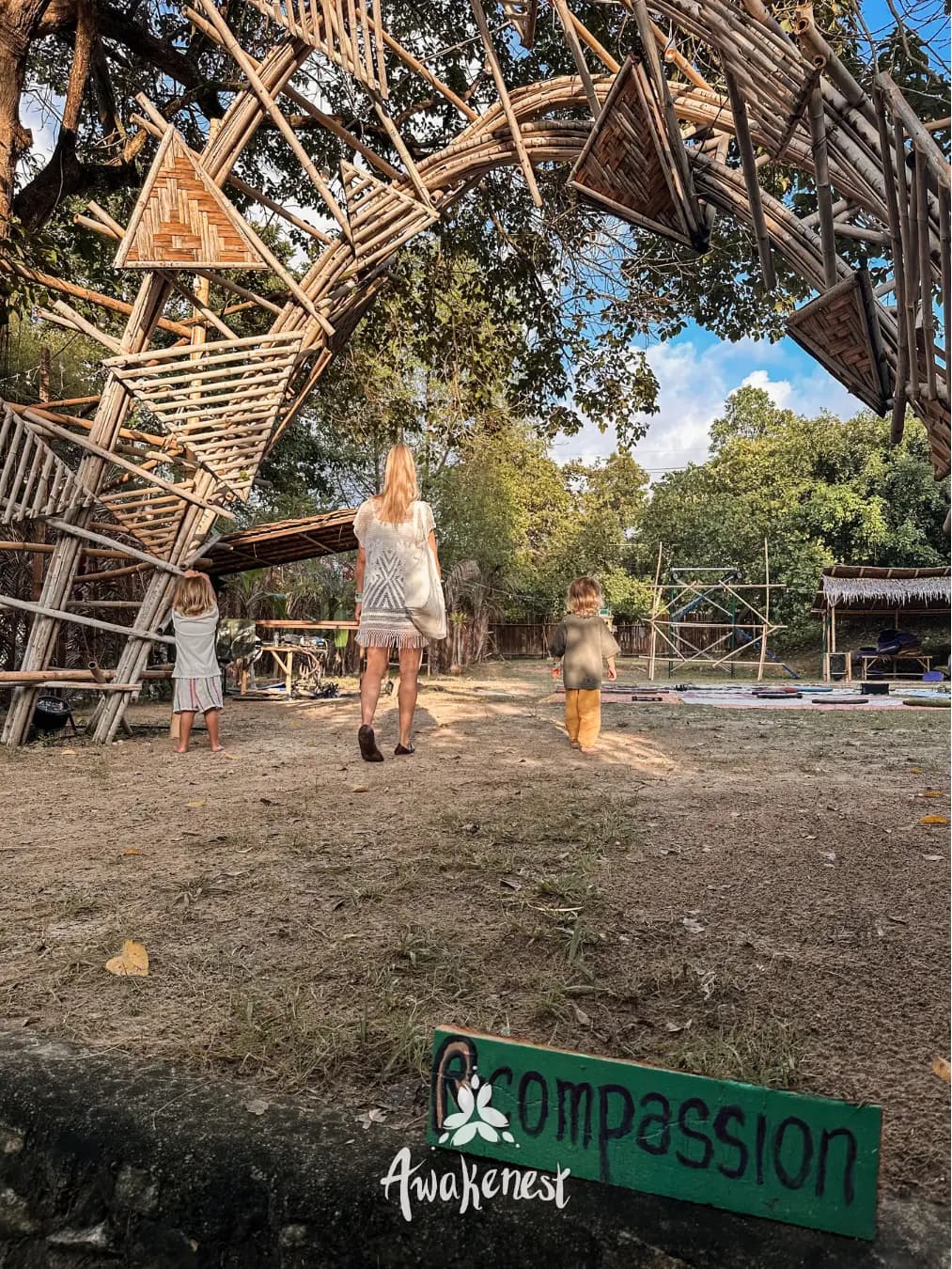 Woman and children walking under bamboo art installation.