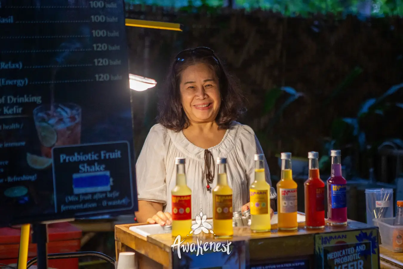 Woman smiles behind kefir drink stand.