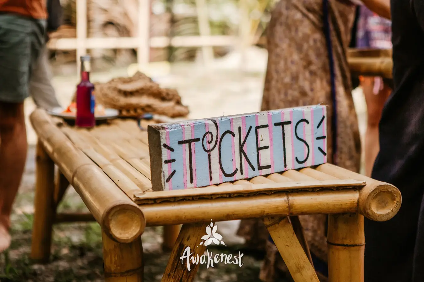 Hand-painted tickets sign on bamboo bench.