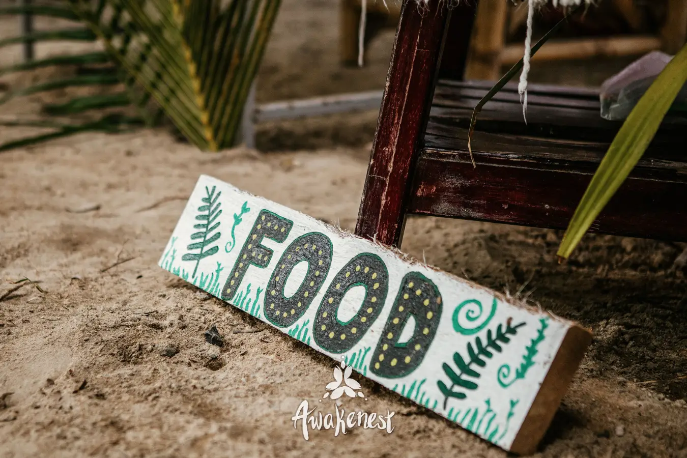 Hand-painted wooden FOOD sign in sand.
