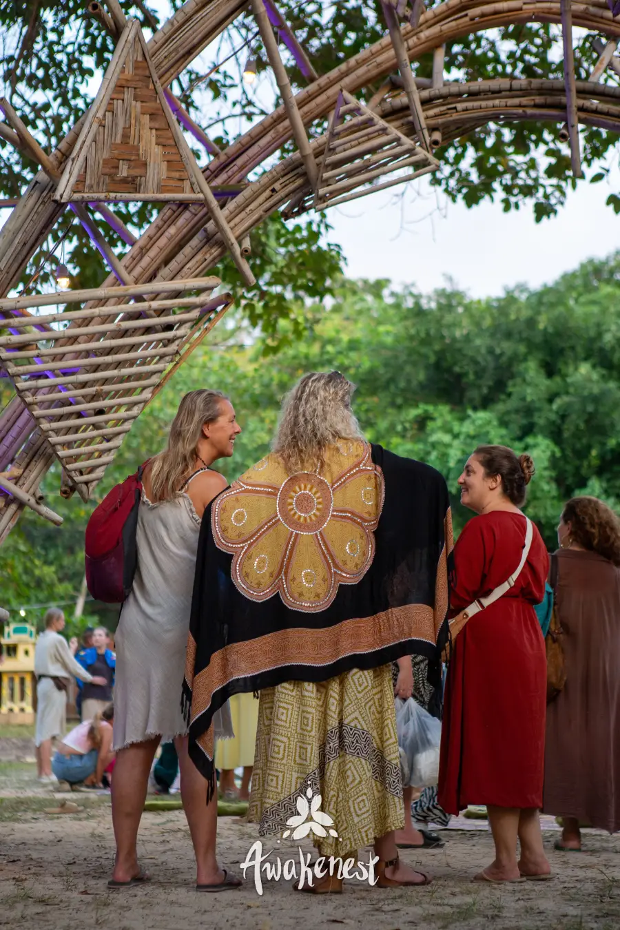 Women in cultural dress beneath bamboo archway.