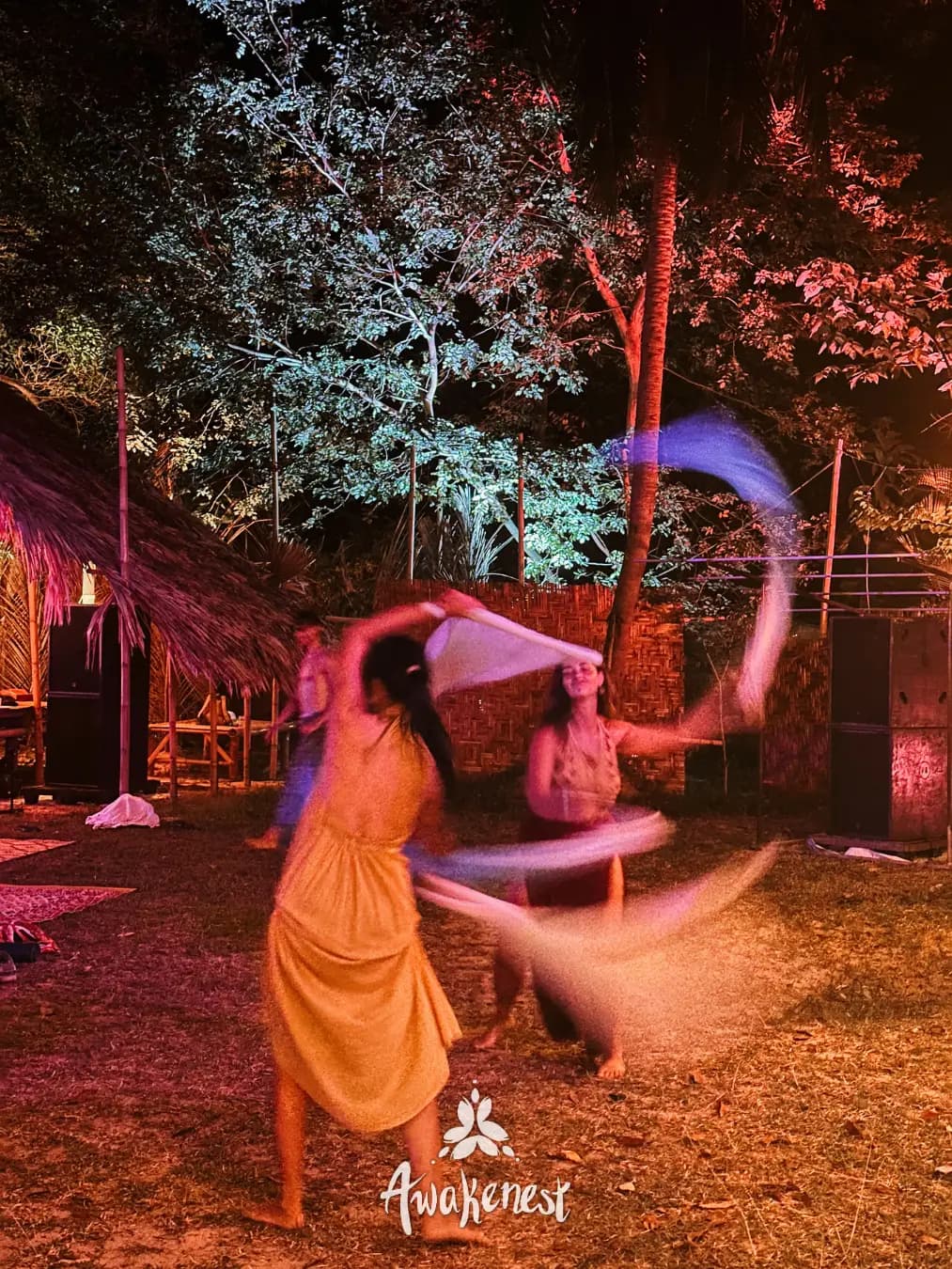 Dancer whirls fabric under colorful night lights.