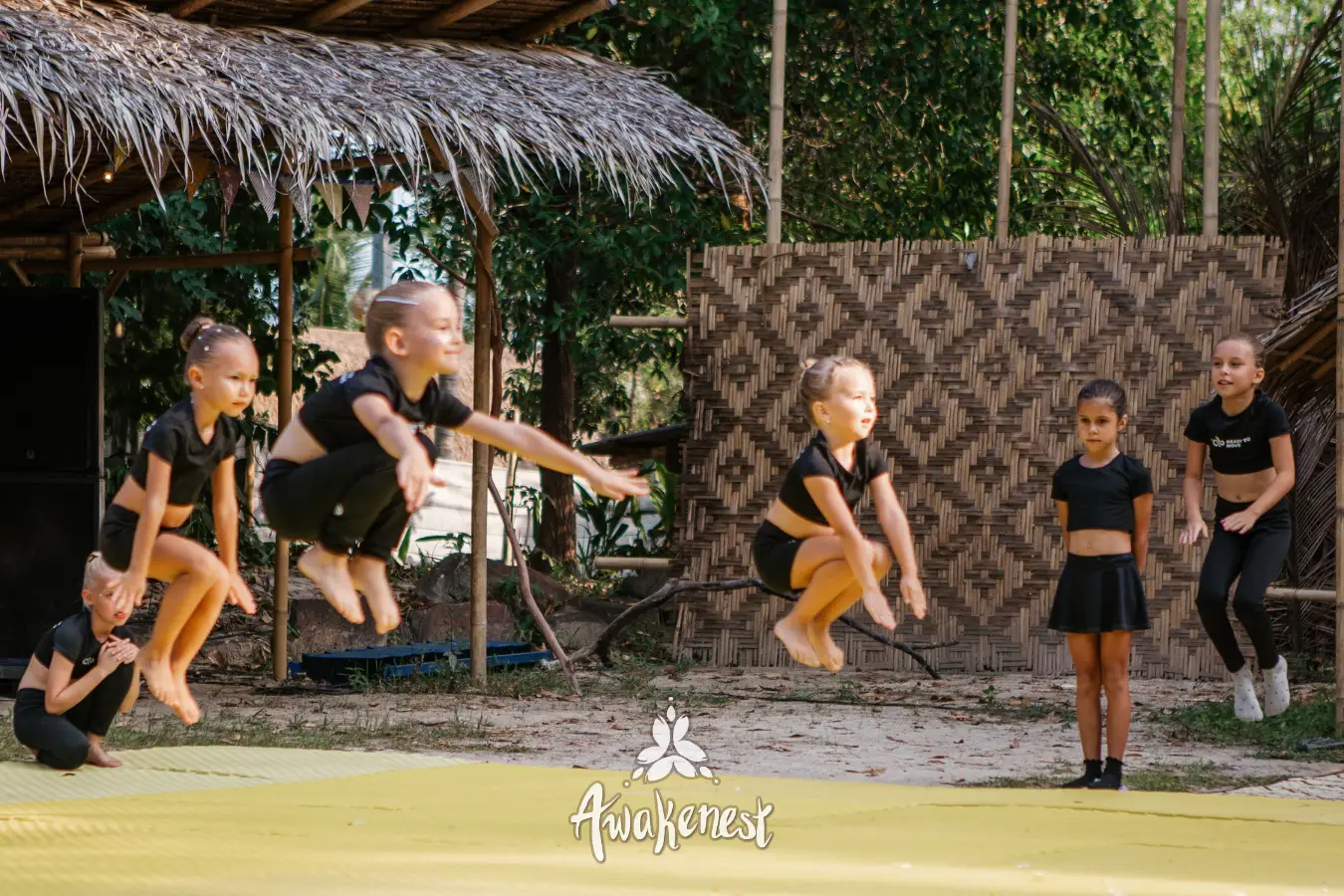 Kids gymnastics team jumps in matching outfits.